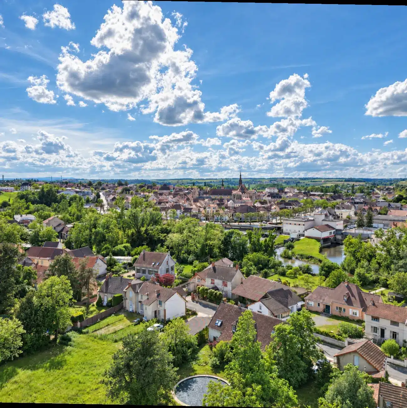 Femme assise dans l'alcôve d'une grande fenêtre en bois, avec vue sur Saint-Pourçain-sur-Sioule, son église et la Sioule